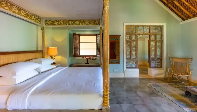 Outdoor lounge area with a rustic table, traditional lighting, and view into the bedroom at Villa Angsa