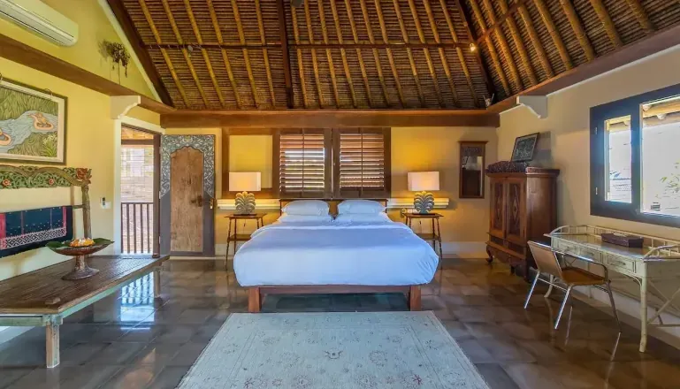 Vibrant bedroom with light green walls, a large bed with a canopy frame, and detailed wooden door at Villa Angsa