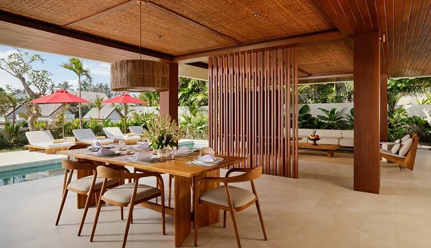 Elegant villa outdoor dining area with a large wooden table set for six guests next to the swimming pool Amarta Beach Retreat 2BR Villa
