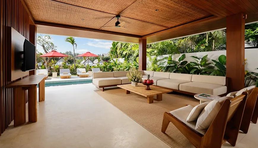 Spacious two bedroom villa living room with natural wood furnishings overlooking the private swimming pool area at Amarta Beach Retreat 2BR Villa