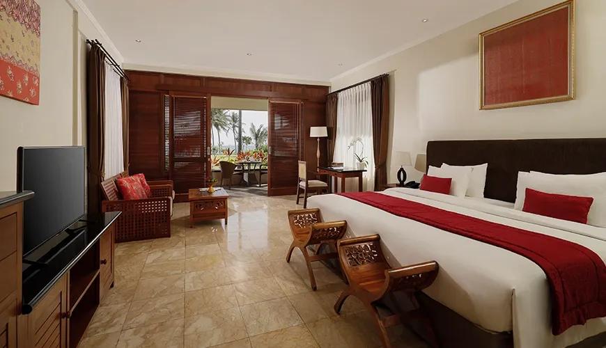 Elegant beachfront bedroom with rich wood paneling and a private terrace at amarta beach retreat