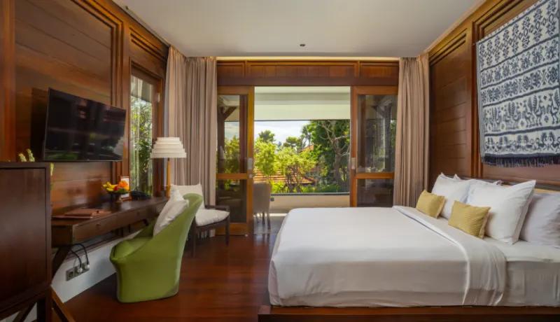 Elegant cabin style master bedroom with dark wood walls and white bedding overlooking a tropical garden at Amarta Beach Retreat