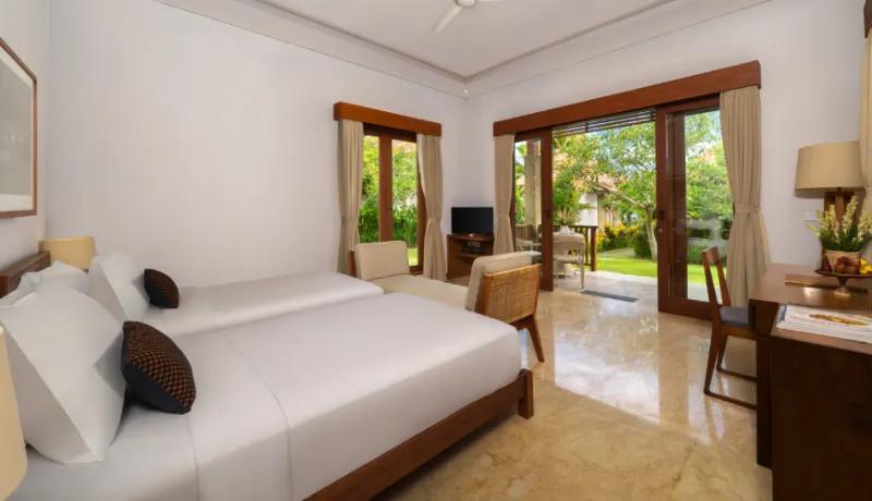 Spacious resort bedroom including twin beds and a private terrace overlooking the vibrant outdoor garden at Amarta Beach Retreat