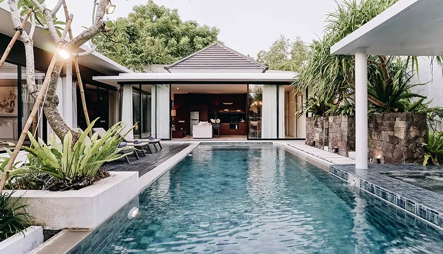 Luxury villa private swimming pool reflecting the bright sky surrounded by beautiful tropical plants and comfortable sun loungers for peaceful relaxation at Ambergris Villa