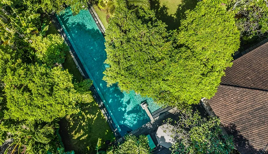 Aerial image showing a beautiful villa rental featuring a long rectangular pool and dense tropical garden foliage at Asraya Villa