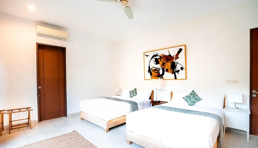 Airy twin bedroom suite with two comfortable beds, minimalist decor, ample natural light, and unique wall art at Asraya Villa