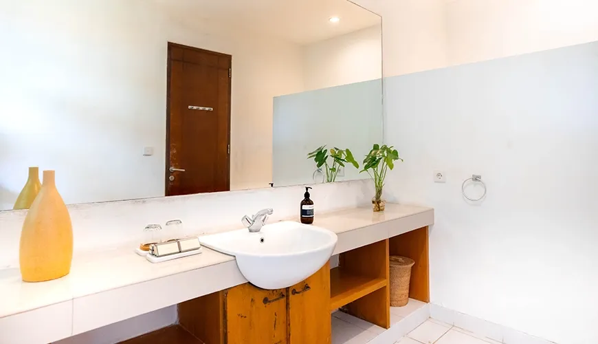 Bright villa guest bathroom featuring a clean vessel sink, wooden vanity, marble countertop, and a large mirror at Asraya Villa