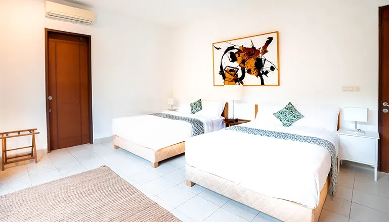 Elegant bedroom design includes twin beds and a striking abstract artwork at Asraya Villa