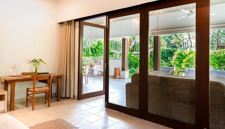 Serene villa suite interior with a small wooden desk, dark wood door frames, and expansive views of the outdoor patio at Asraya Villa
