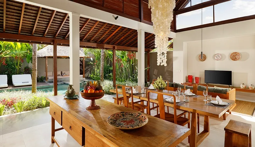 Spacious villa dining area large wooden tables shell chandelier pool view at Bumbak Park