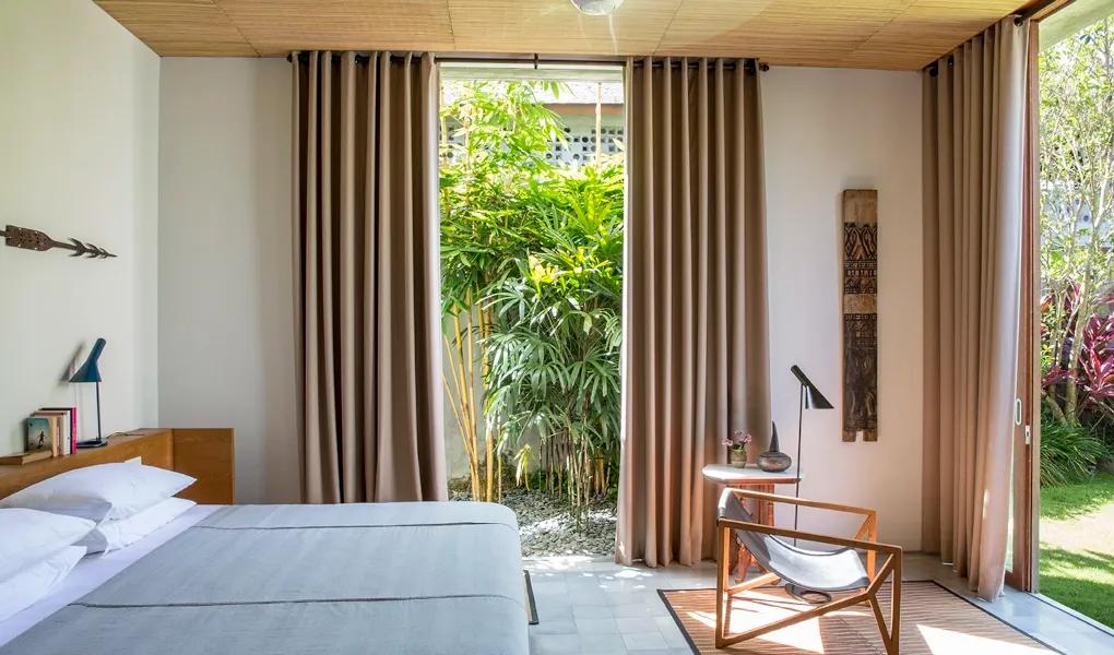 Bright bedroom with large windows overlooking tropical garden at casaBama