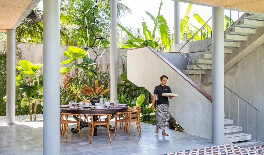 Elegant dining setting with a server and tropical foliage at casaBama