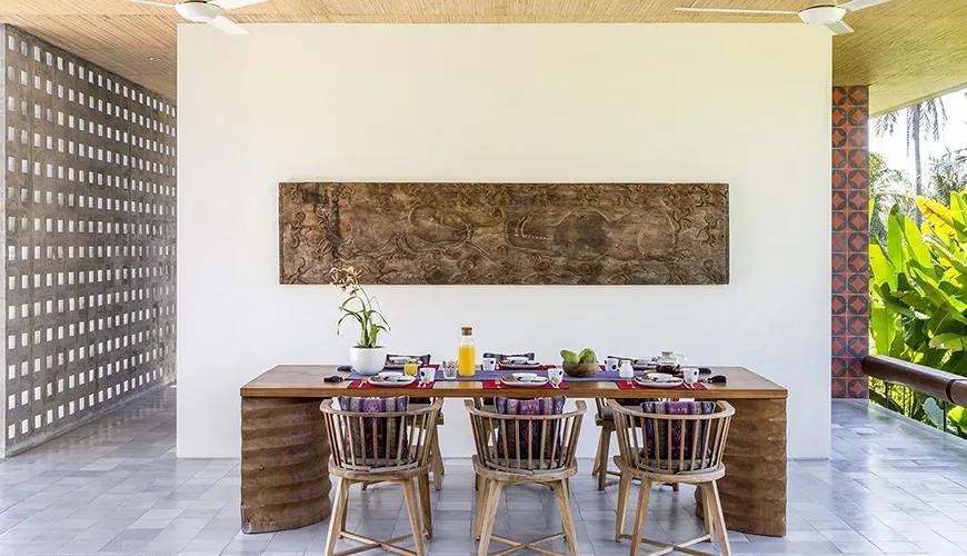 Open-air dining area features a large table and ornate carved wall art at caSabama