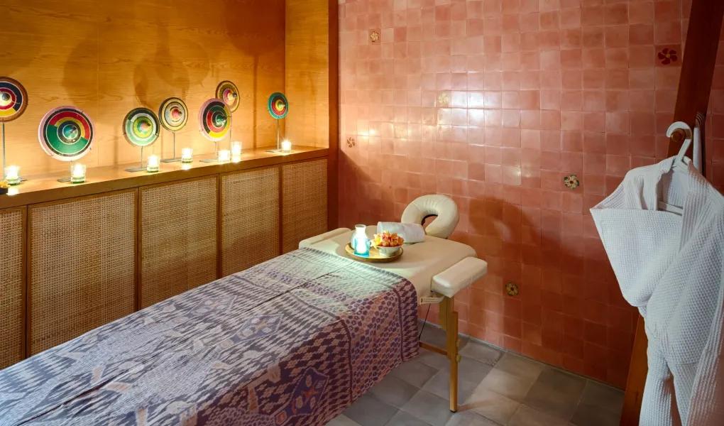 Spa room with massage bed, colorful art, and robe at casaBama