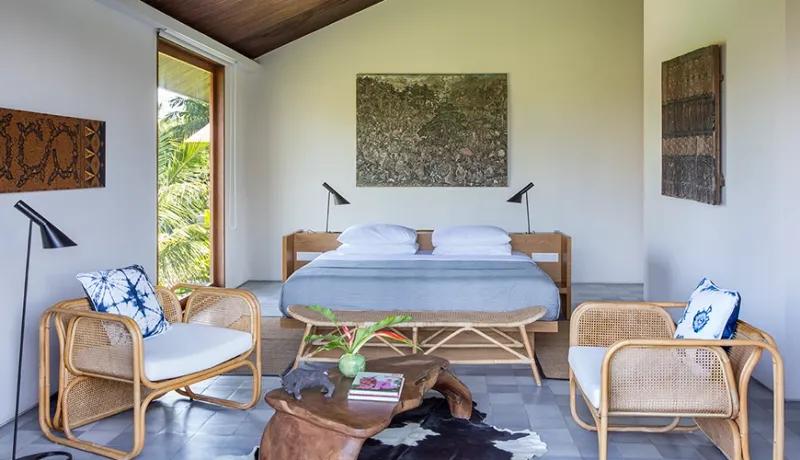 Spacious master bedroom villa featuring a king bed rattan accent chairs and lush tropical garden views at Casabama