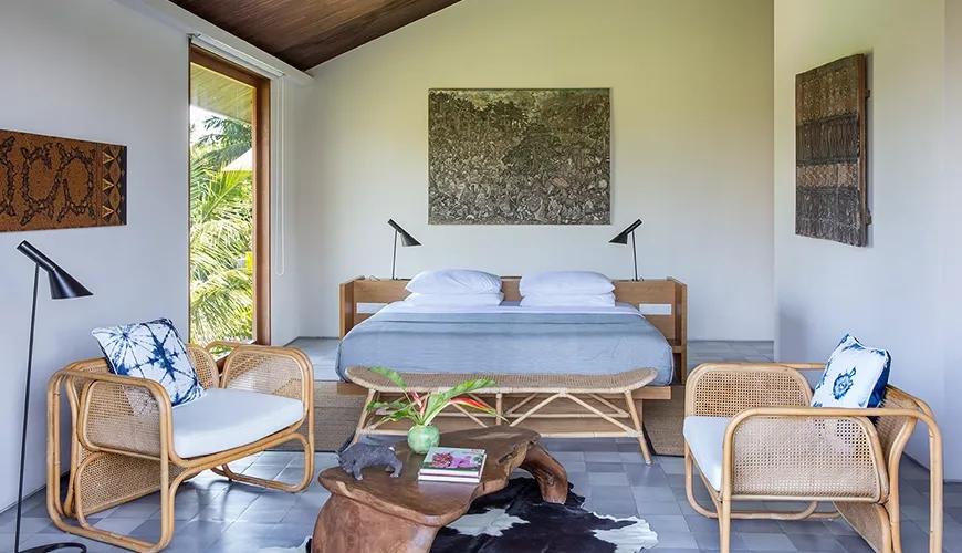 Spacious master bedroom villa featuring a king bed rattan accent chairs and lush tropical garden views at Casabama