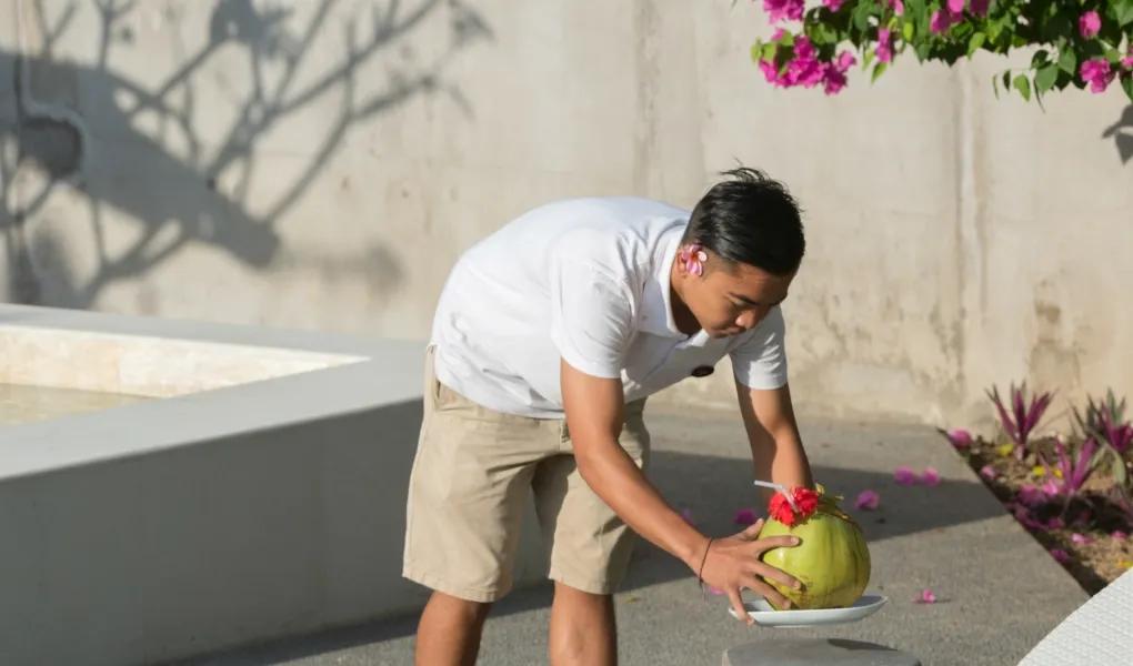 Staff member serving a fresh coconut by the pool at casaBama