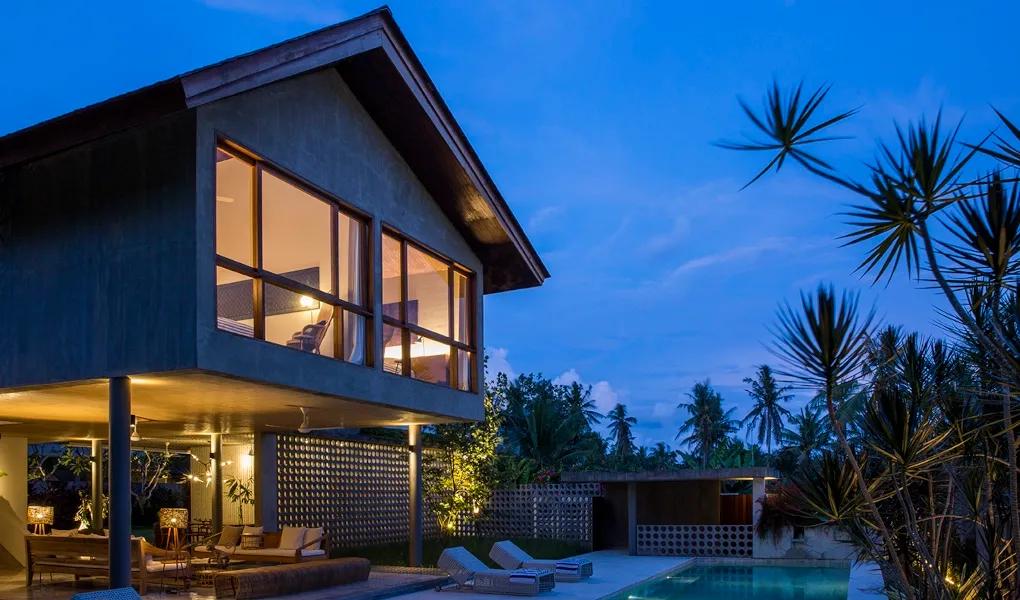 Tropical villa with a pool lit up at dusk at casaBama