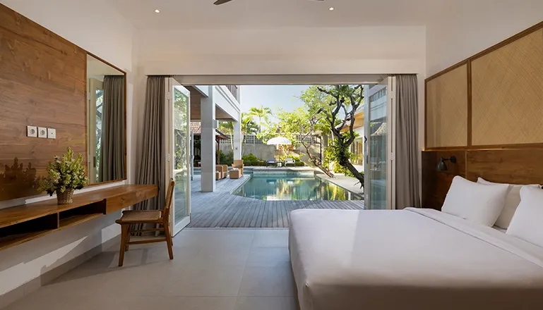 Bright bedroom with a large bed opening to pool view at Christie Villa