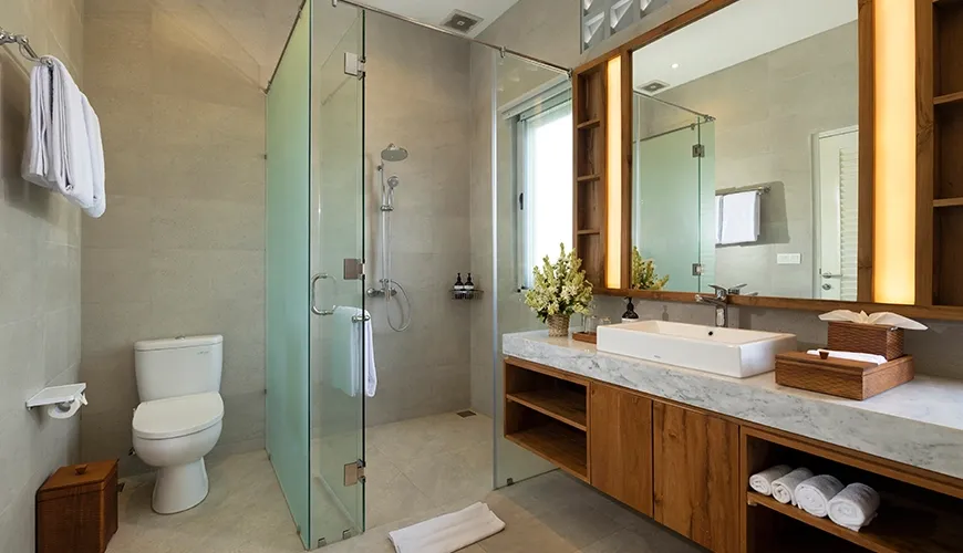 Clean and contemporary bathroom featuring a glass enclosed shower and a sleek wooden vanity with a large mirror at Christie Villa