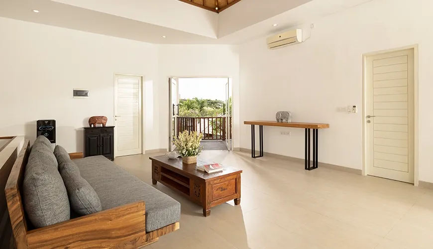 Comfortable living room featuring a modern grey sofa and a wooden coffee table with a fresh flower arrangement at Christie Villa