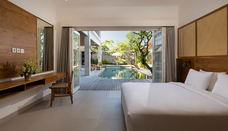 Cozy and modern bedroom with a large glass door opening to a private swimming pool with outdoor seating at Christie Villa