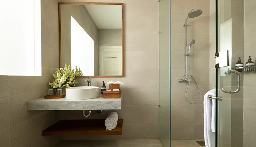 Minimalist and clean bathroom with a modern circular sink on a marble countertop and a clear glass shower at Christie Villa