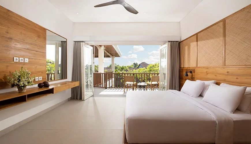 Spacious and inviting bedroom with a comfortable white bed and a private balcony overlooking the lush treetops at Christie Villa