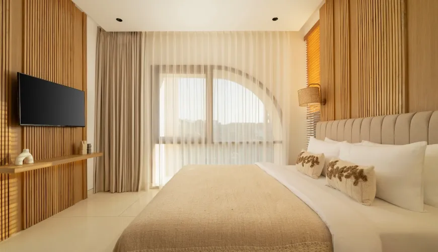 Neutral tone bedroom with arched window and a mounted TV at Fenta Villa