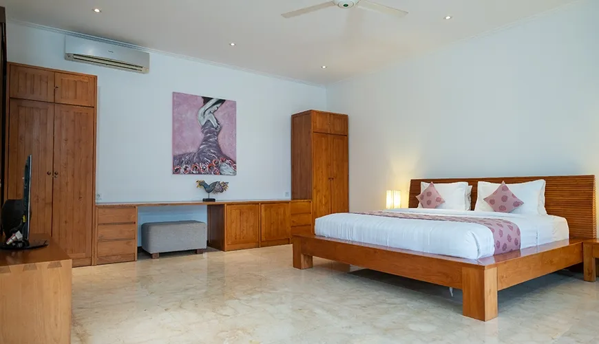Spacious contemporary villa bedroom with polished marble floor, light wooden platform bed, and built-in storage at Istana Putih Villa