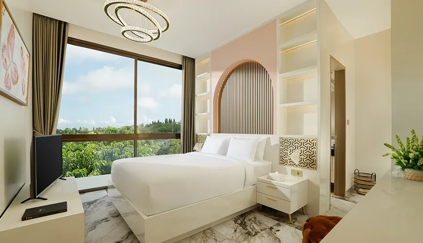 Stylish bedroom has a large window that overlooks a lush green landscape and trees at Kalem Uluwatu