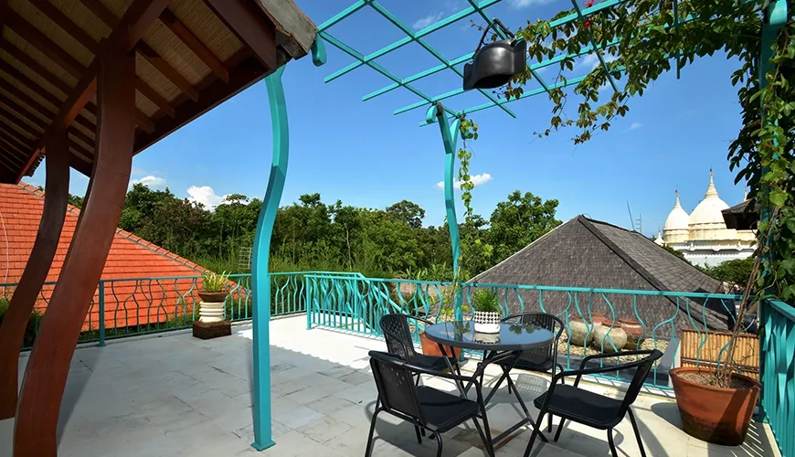 A beautiful rooftop terrace with an outdoor dining set and a turquoise canopy offering a tropical view at Kama Village 1BR