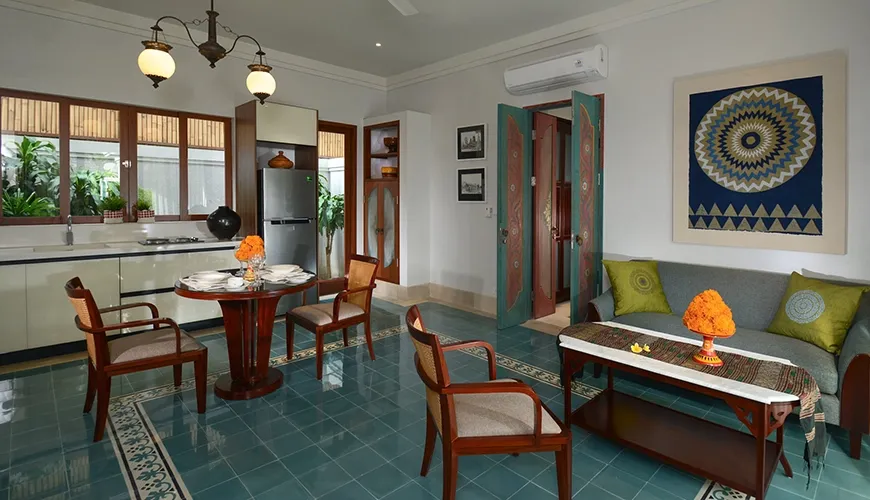 A traditional Bali-themed living and kitchen area featuring beautiful blue tile floors and authentic wooden furniture at Kama Village 1BR
