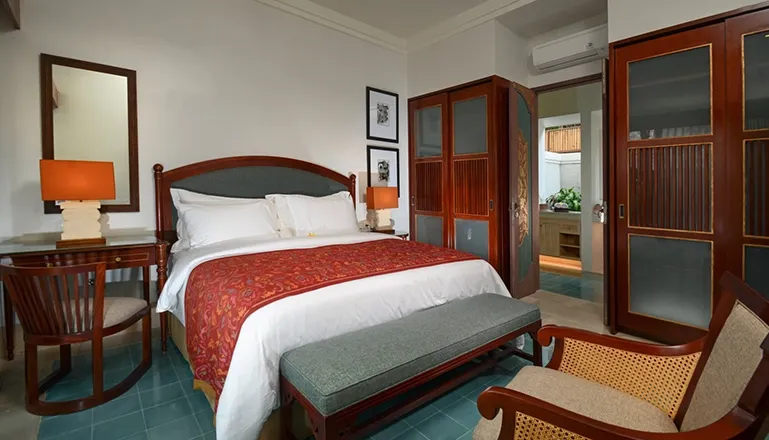 A traditional master bedroom featuring a luxurious red and blue theme with beautiful wooden furniture at Kama Village 1BR