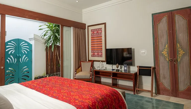 Elegant master bedroom suite featuring traditional red and blue decor with beautiful wooden furniture at Kama Village 1BR