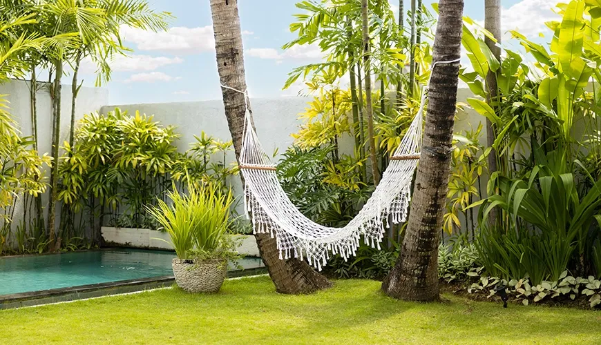 Villa tropical garden hammock beside green swimming pool at Kuma Umalas Villa
