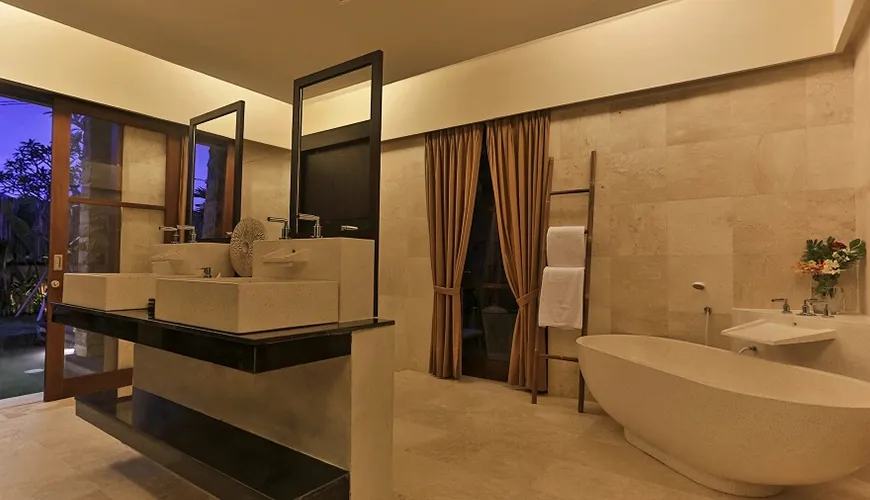 Elegant twin vanity area with custom mirrors and glass doors opening to a beautiful private outdoor evening garden view at Kumuda Villa