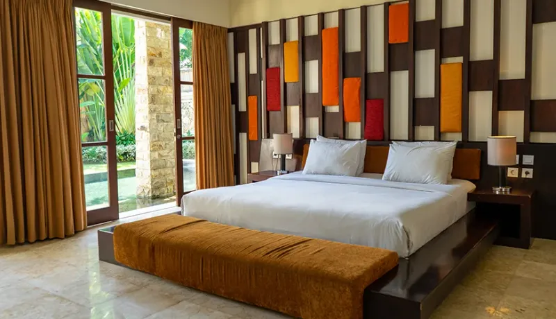 Relaxing bedroom with a king bed and tranquil pool vista at Kumuda Villa