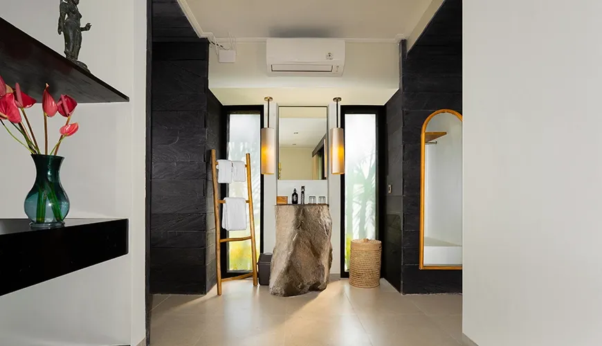 Chic villa bathroom featuring a unique stone pedestal sink and black textured walls with bright lighting at Le Sunset Villa
