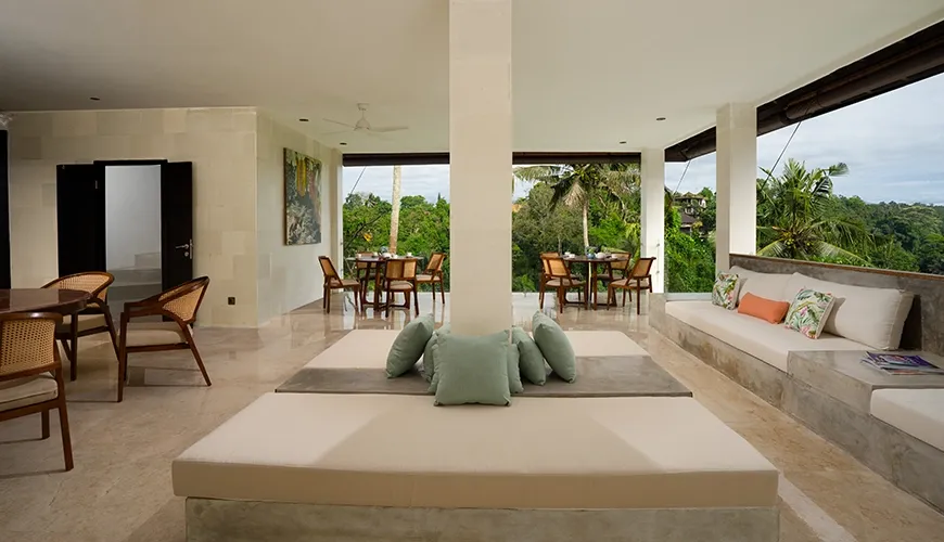 Expansive open concept luxury villa living area with comfortable daybeds and dual dining tables facing outdoors at Le Sunset Villa