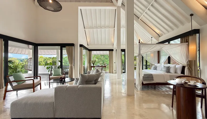 Grand master bedroom villa suite featuring a four poster canopy bed and spacious modern lounge seating area at Le Sunset Villa