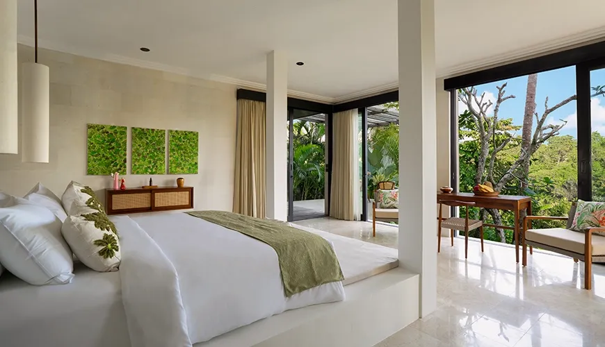 Modern villa bedroom with platform bed, marble floors, and sliding glass doors opening to green views at Le Sunset Villa