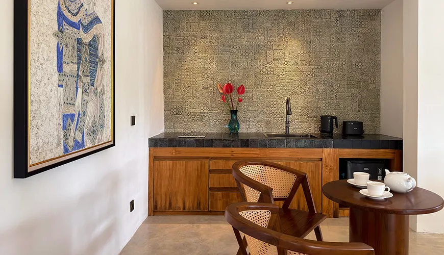 Modern villa kitchenette area with wooden cabinets, a unique tiled backsplash, and local artwork displayed at Le Sunset Villa