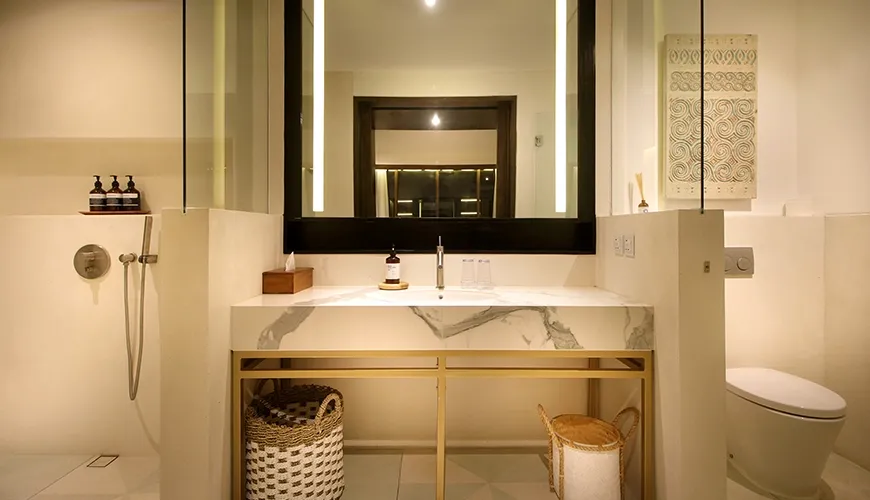 Contemporary villa bathroom featuring a sleek marble vanity, gold accents, and a large backlit mirror at Leceni Villa