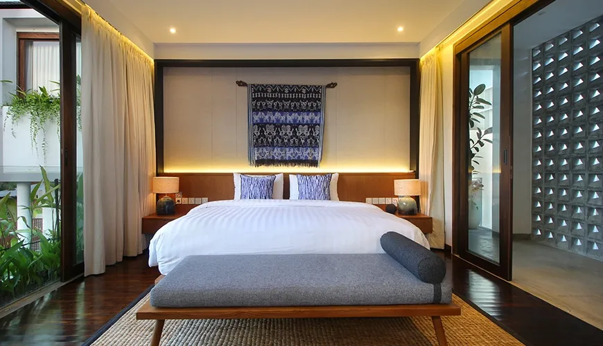 Inviting modern bedroom with soft ambient backlighting and large sliding glass doors opening to tropical gardens at Leceni Villa