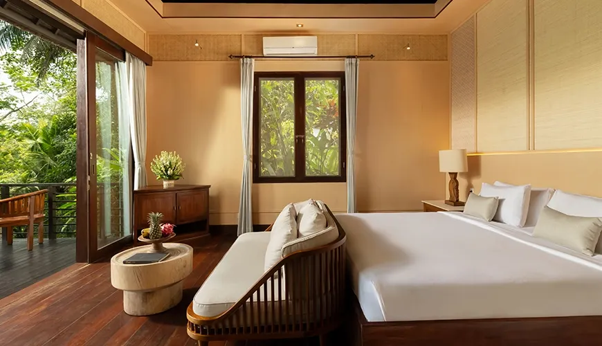 Beautiful master bedroom offering a private balcony overlooking a serene tropical landscape at Leona Suweta