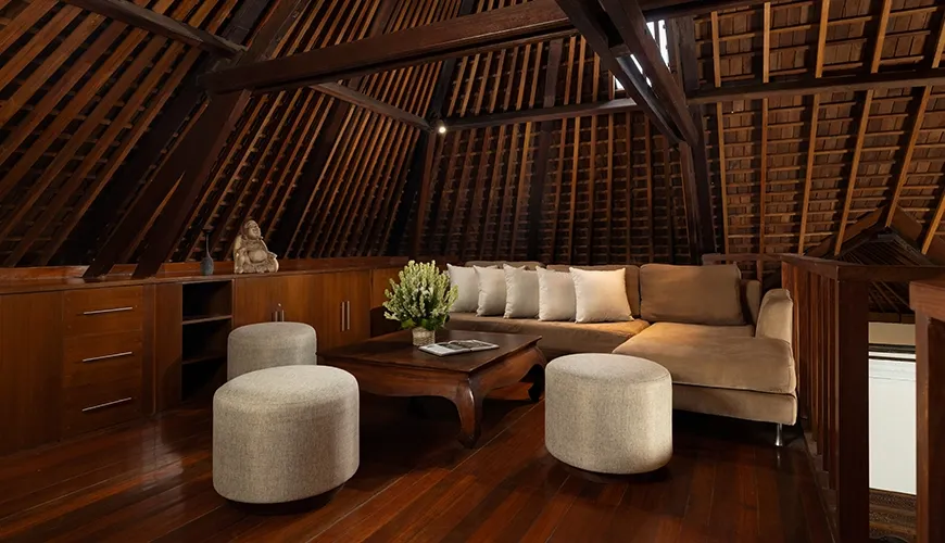 Cozy attic lounge area featuring sloped wooden ceiling and comfortable ample seating at Leona Suweta