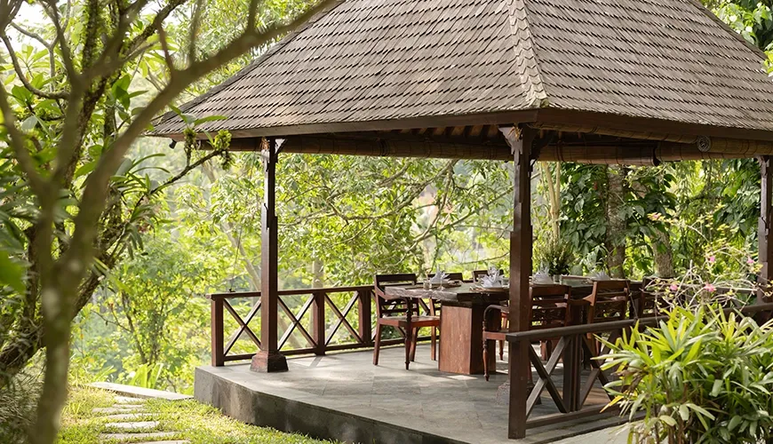 Outdoor dining gazebo with wooden table and chairs amidst lush green surroundings at Leona Suweta