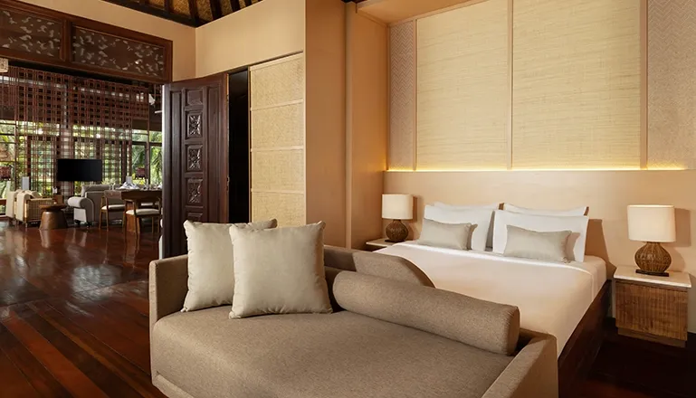 Spacious bedroom with daybed and wooden doors leading to a living area at Leona Suweta