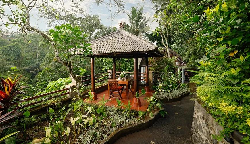 Outdoor dining bale with a wooden table is surrounded by lush tropical jungle and foliage at Leona Valley View 1BR